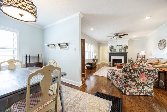 dining space with crown molding, a fireplace, baseboards, and wood finished floors