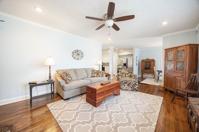 living room featuring decorative columns, ornamental molding, ceiling fan, wood finished floors, and baseboards