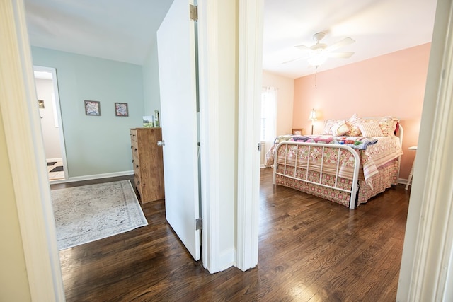 bedroom with dark wood-type flooring, a ceiling fan, and baseboards