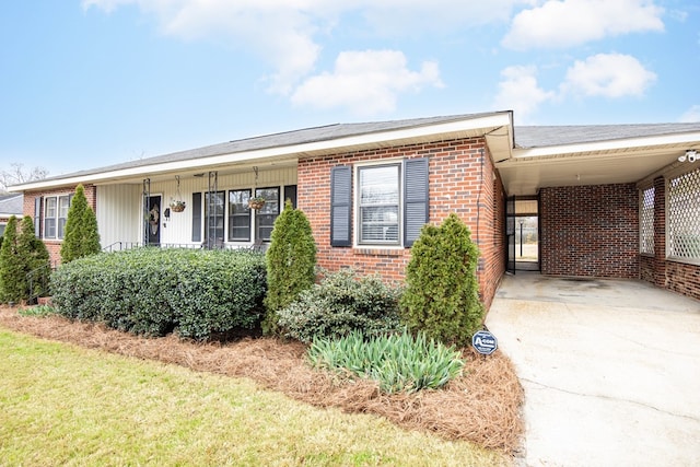 ranch-style house with driveway, brick siding, and an attached carport