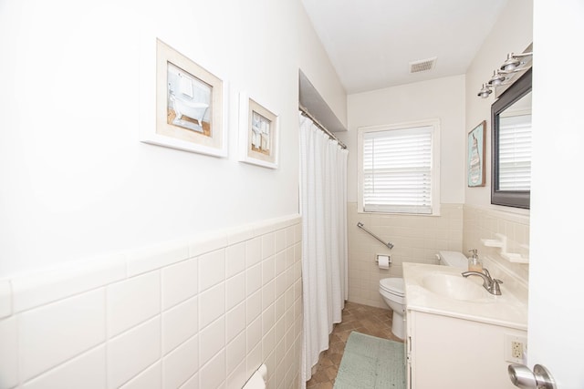 bathroom with tile patterned flooring, toilet, a wainscoted wall, vanity, and visible vents