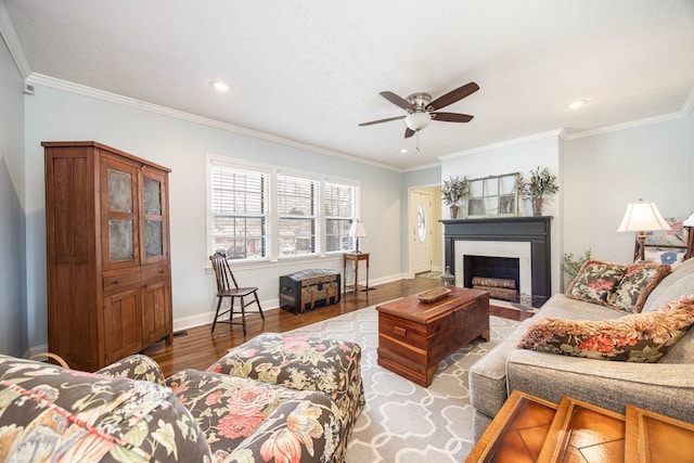 living area featuring a ceiling fan, baseboards, ornamental molding, and wood finished floors