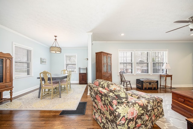 living area featuring crown molding, a textured ceiling, baseboards, and wood finished floors