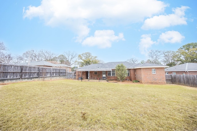 back of property featuring a patio, brick siding, a lawn, and a fenced backyard