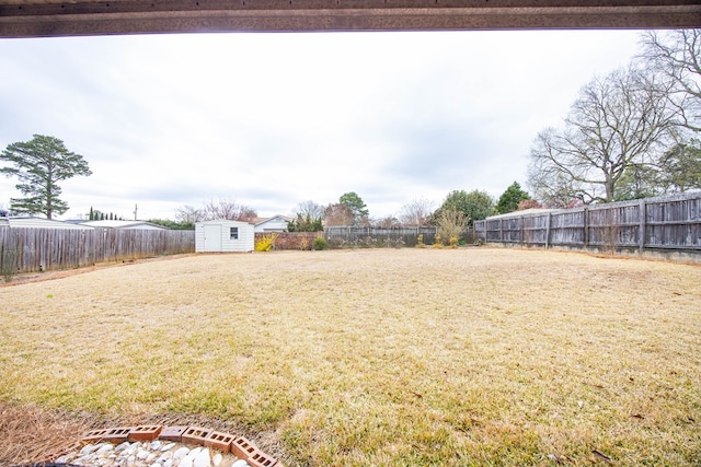 view of yard featuring a storage shed, a fenced backyard, and an outdoor structure