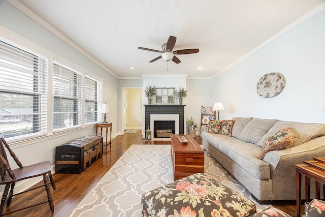 living area with a fireplace with flush hearth, crown molding, baseboards, and wood finished floors