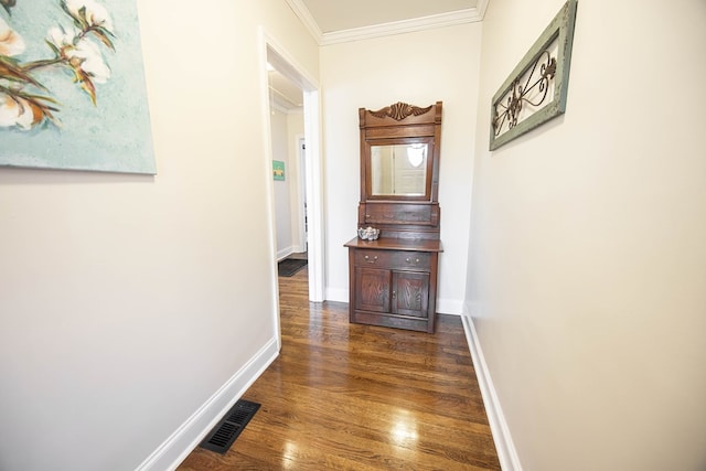 hallway with ornamental molding, dark wood-style flooring, visible vents, and baseboards