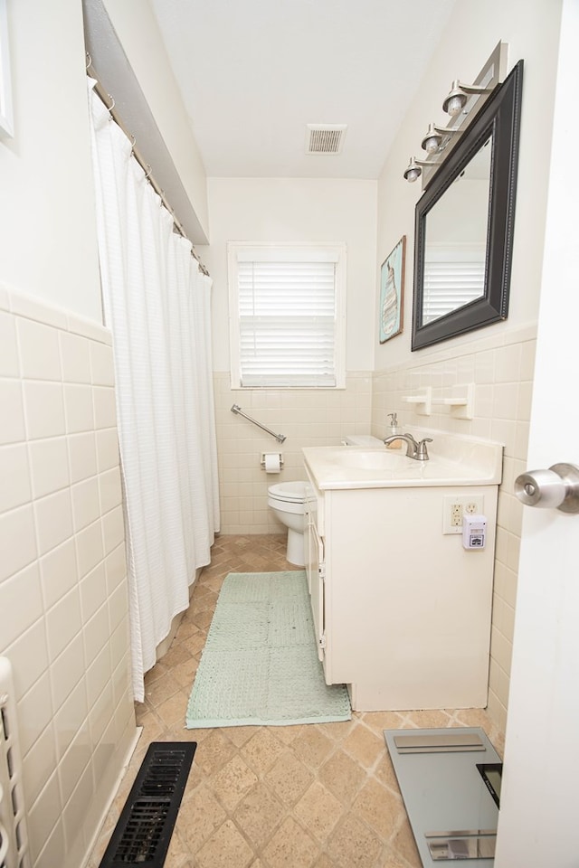 bathroom featuring visible vents, tile walls, toilet, and vanity