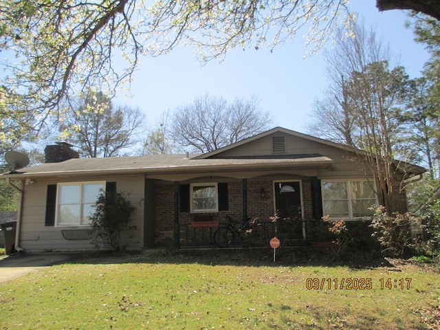 view of front of property featuring a front lawn, a porch, brick siding, and a chimney