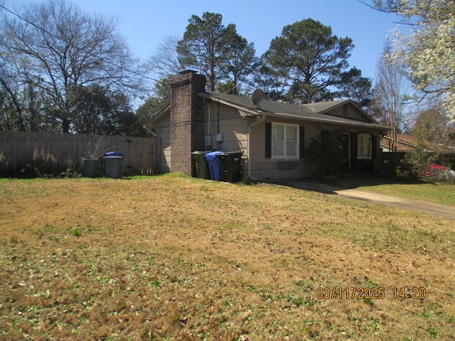 view of property exterior featuring a yard, a chimney, and fence