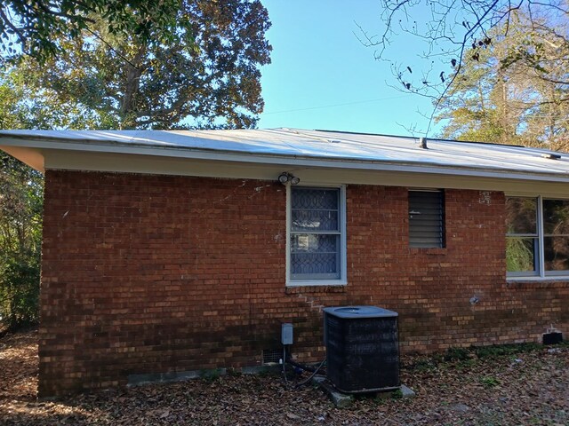 view of property exterior with cooling unit and brick siding