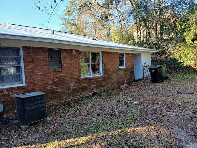 view of side of home with brick siding and central air condition unit