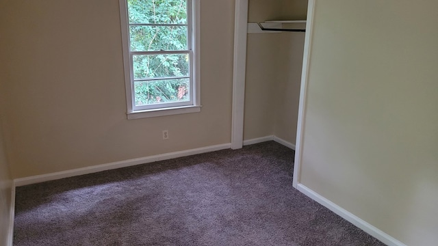 unfurnished bedroom with a closet, baseboards, and dark colored carpet