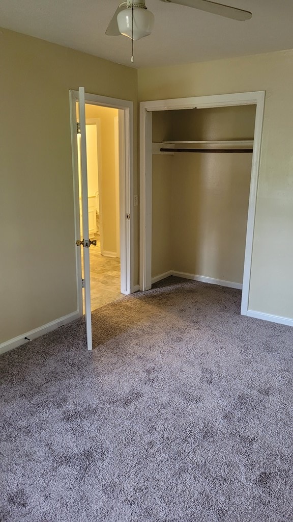 unfurnished bedroom featuring a ceiling fan, carpet flooring, baseboards, and a closet