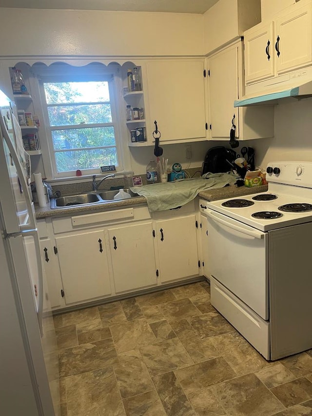 kitchen with a sink, stone finish flooring, under cabinet range hood, white cabinetry, and white appliances