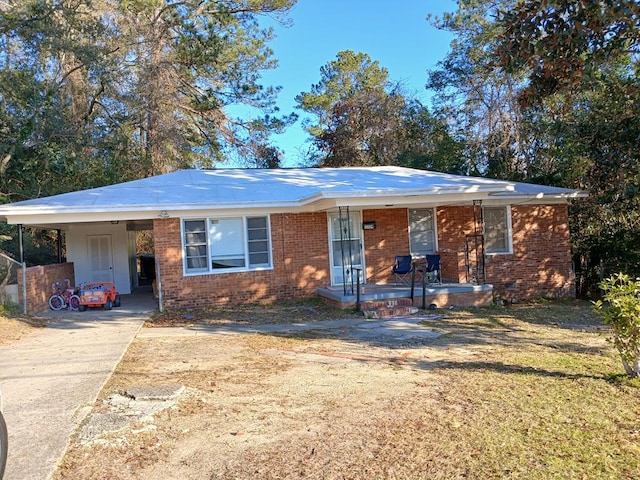 ranch-style home with brick siding, an attached carport, a porch, and concrete driveway