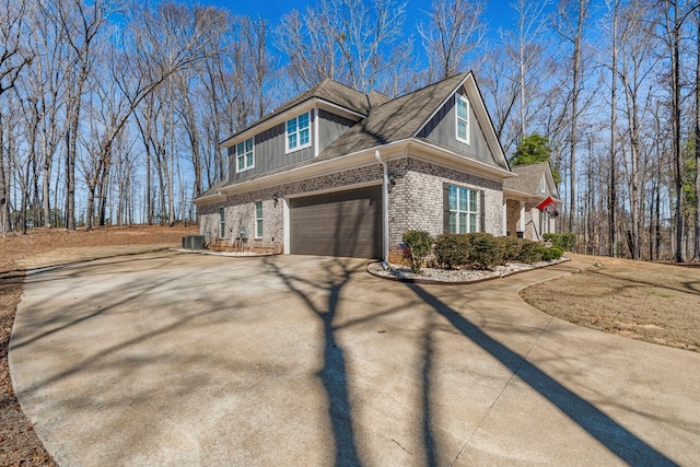 view of side of property featuring concrete driveway, brick siding, and cooling unit