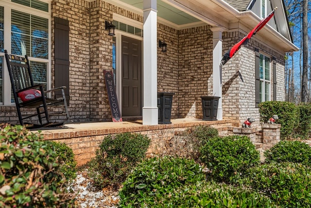 property entrance featuring covered porch and brick siding