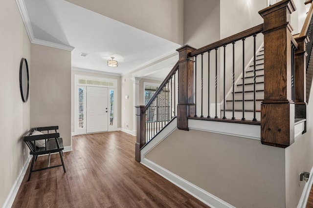 entrance foyer featuring baseboards, wood finished floors, decorative columns, and crown molding