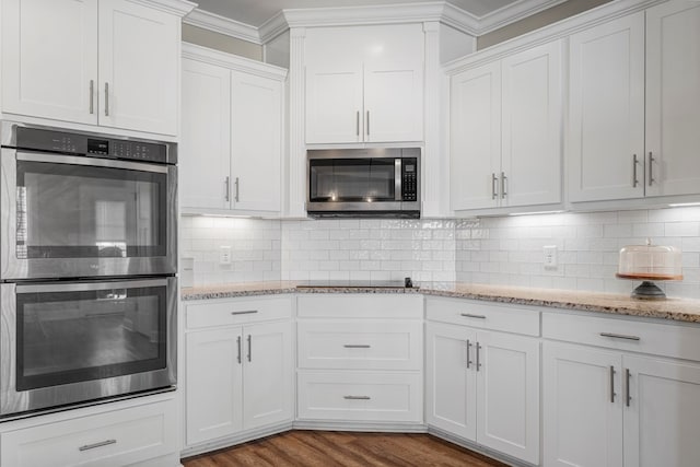 kitchen featuring dark wood-style flooring, white cabinets, ornamental molding, appliances with stainless steel finishes, and tasteful backsplash