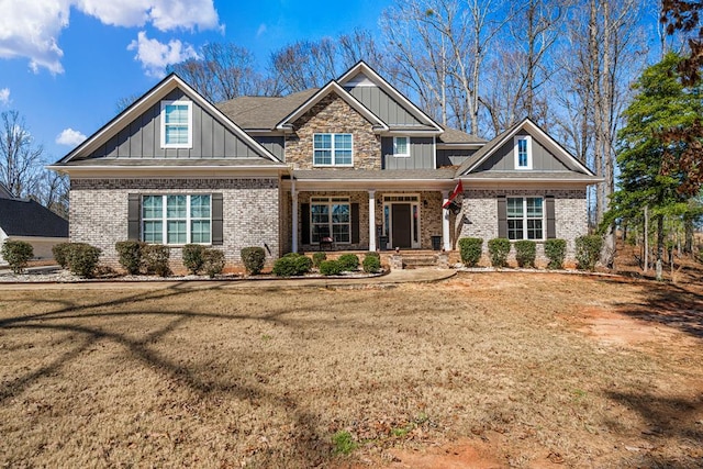 craftsman house featuring a front yard, a porch, board and batten siding, and brick siding