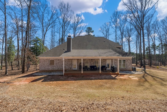 back of house featuring a patio area, a yard, a chimney, and brick siding