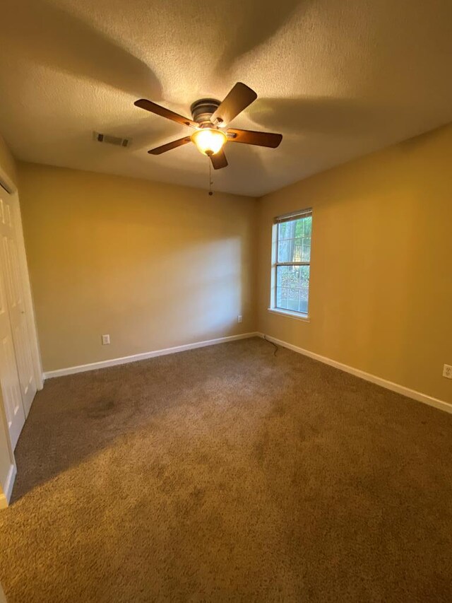 carpeted spare room featuring ceiling fan and a textured ceiling