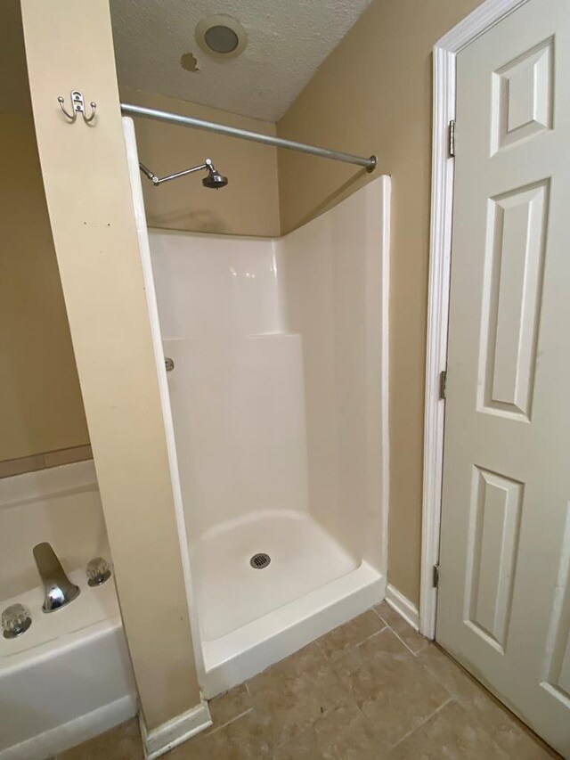 bathroom featuring tile patterned flooring, a shower, and a textured ceiling