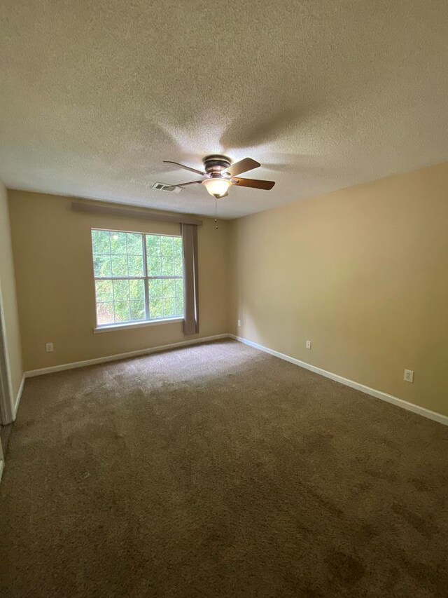 carpeted empty room featuring ceiling fan and a textured ceiling