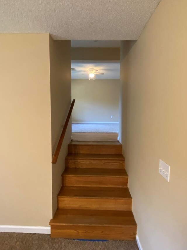 stairs with carpet and a textured ceiling