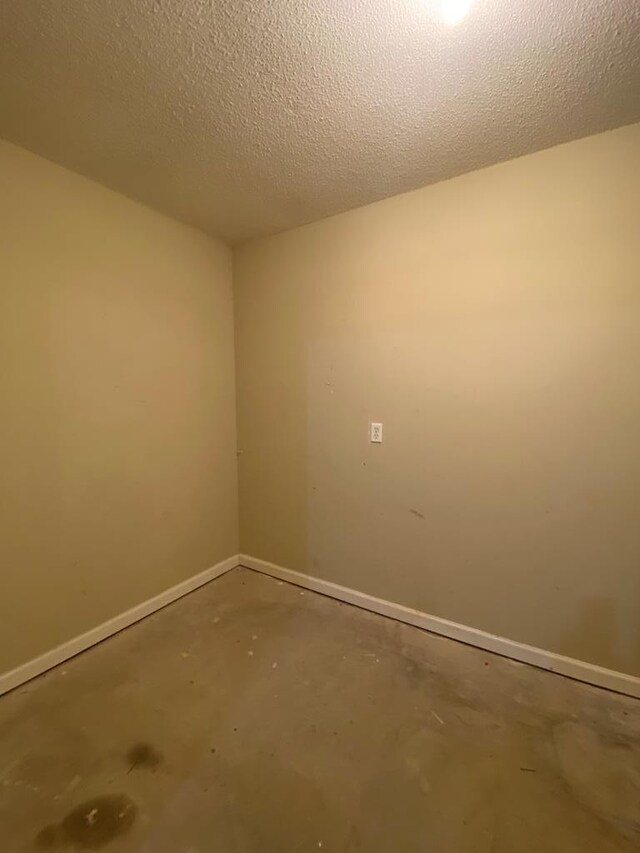 empty room with a textured ceiling and concrete floors