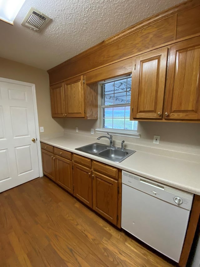 kitchen featuring hardwood / wood-style floors, dishwasher, sink, and a textured ceiling