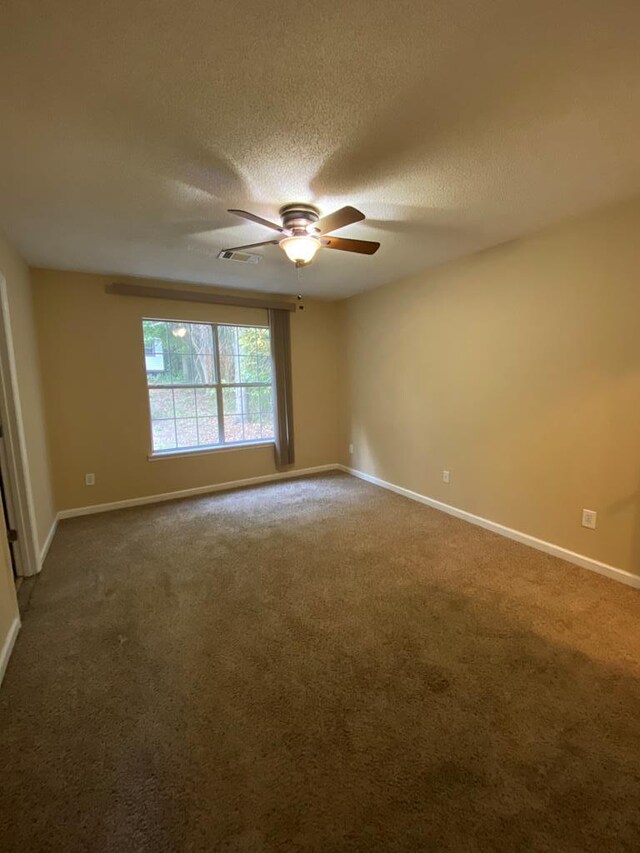 carpeted spare room featuring ceiling fan and a textured ceiling