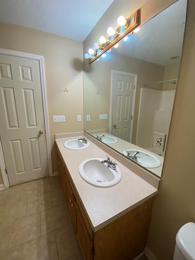 bathroom featuring walk in shower, tile patterned flooring, vanity, and toilet