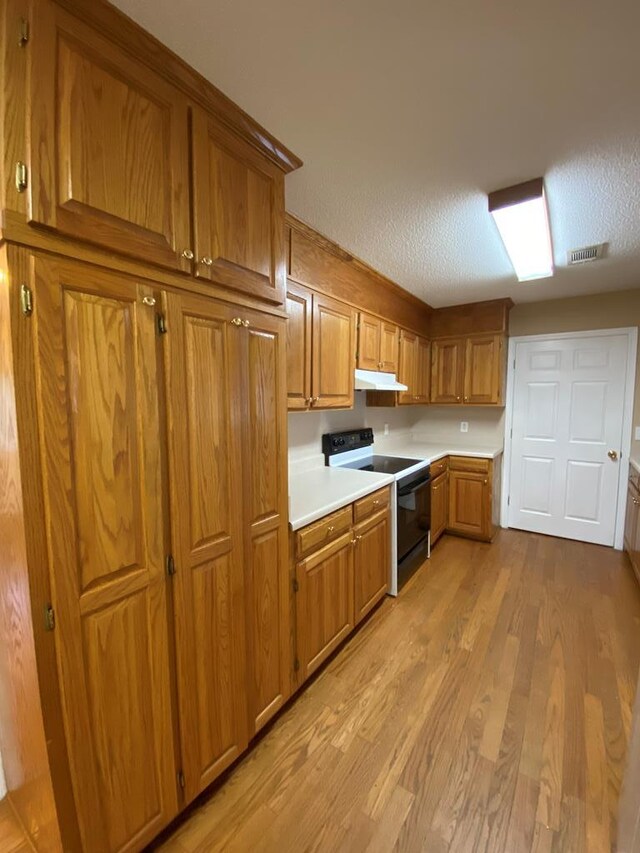 kitchen with electric range, light hardwood / wood-style flooring, and a textured ceiling