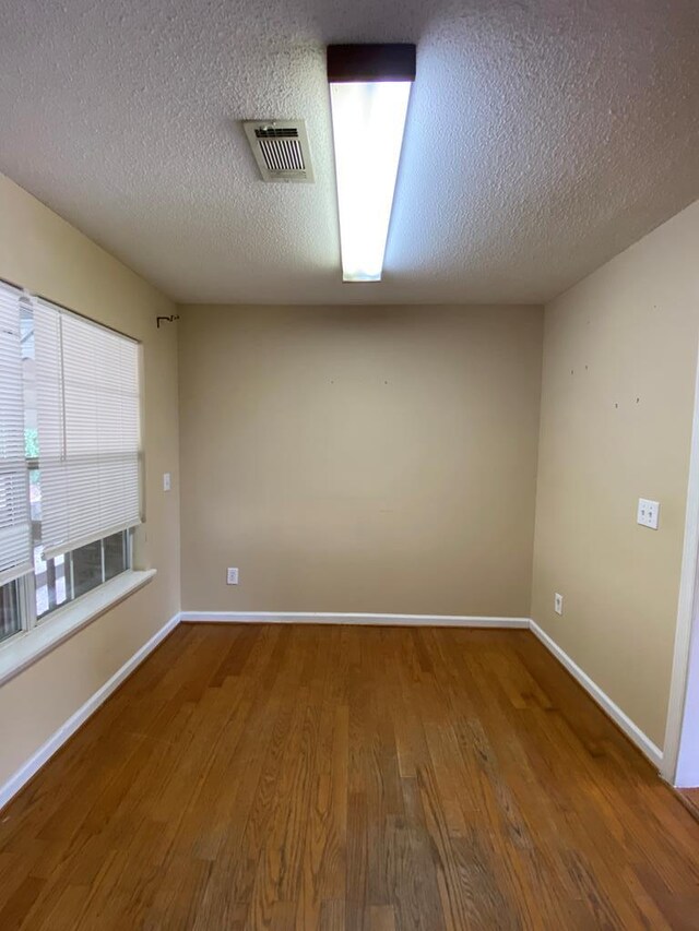 spare room featuring hardwood / wood-style floors and a textured ceiling