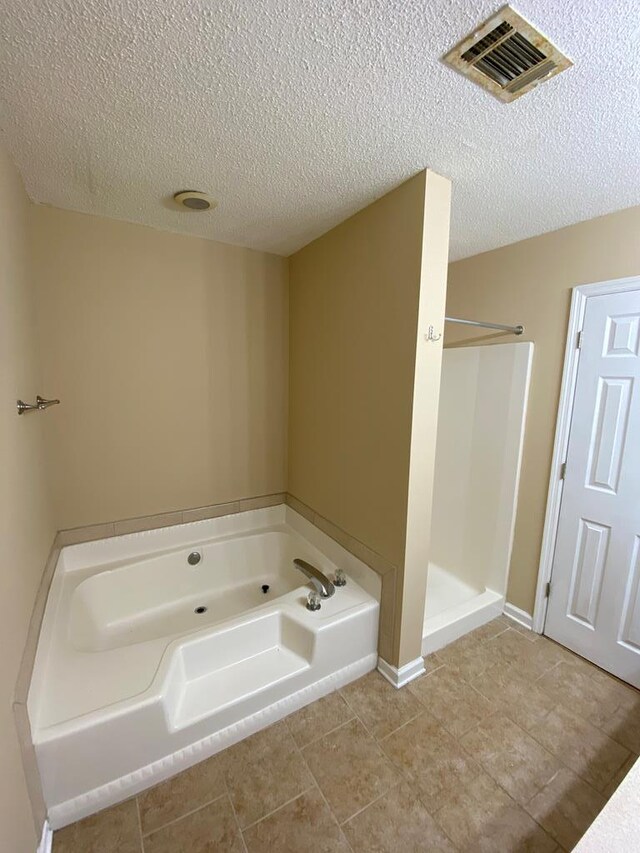 bathroom featuring tile patterned flooring, independent shower and bath, and a textured ceiling