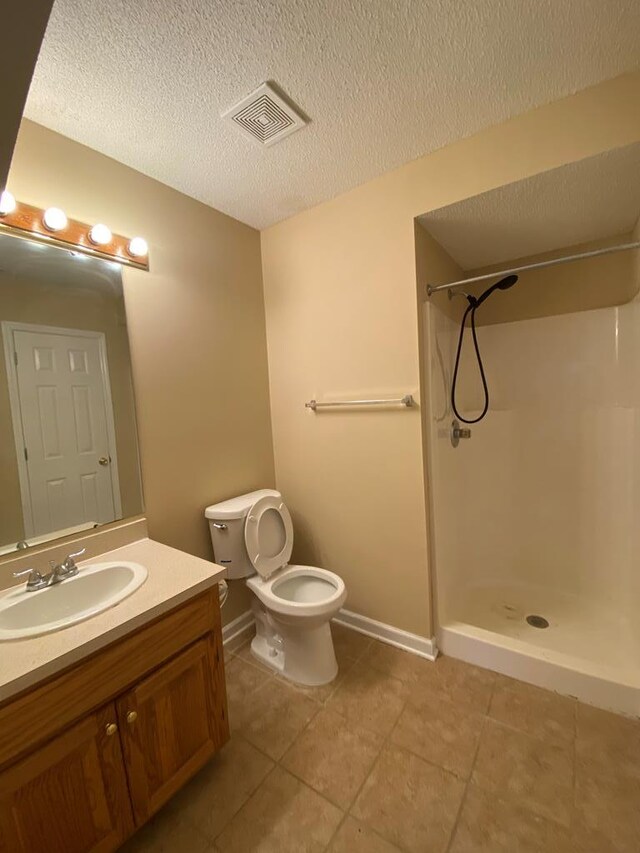 bathroom featuring toilet, tile patterned flooring, vanity, and walk in shower