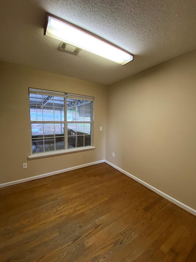 empty room featuring a textured ceiling and dark hardwood / wood-style floors