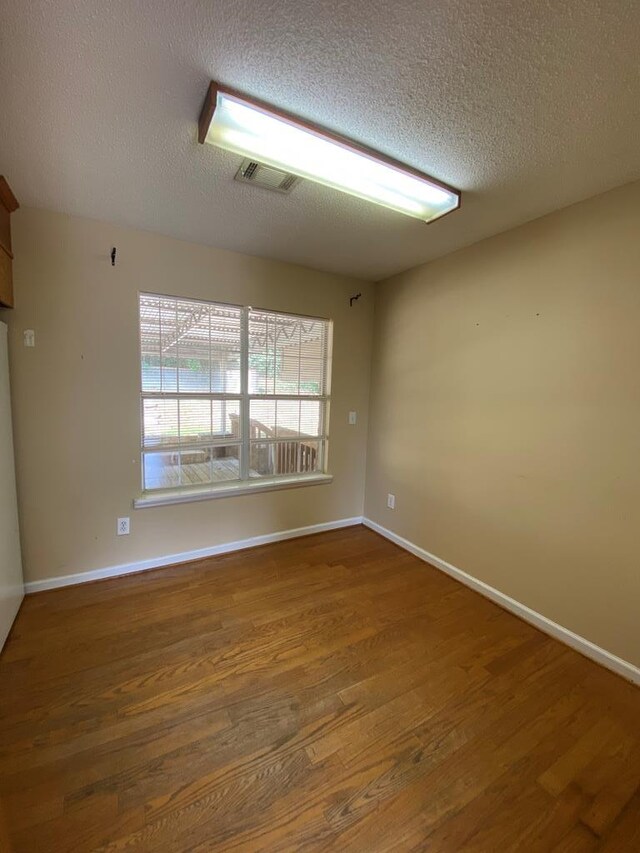 unfurnished room featuring dark hardwood / wood-style flooring and a textured ceiling