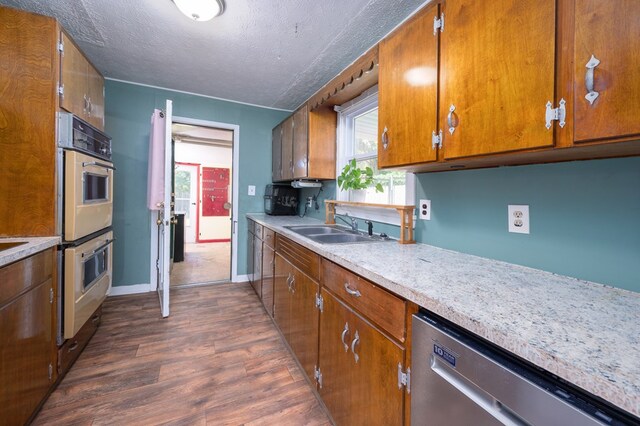 kitchen featuring dishwasher, dark wood-style floors, a textured ceiling, white double oven, and light countertops