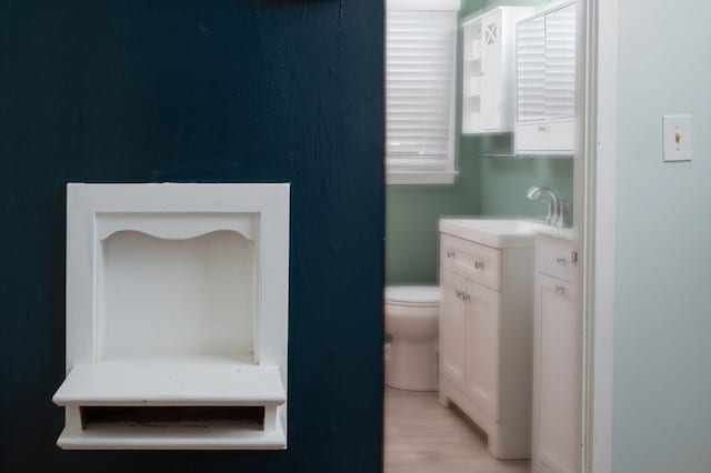 half bathroom with toilet, vanity, and wood finished floors