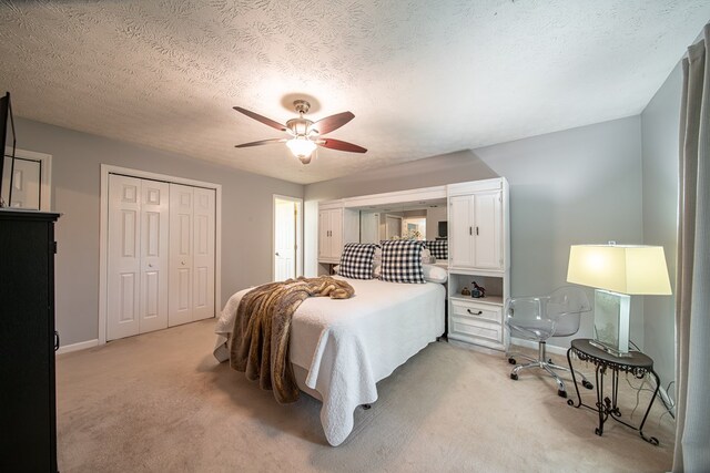 carpeted bedroom with ceiling fan, a closet, and a textured ceiling