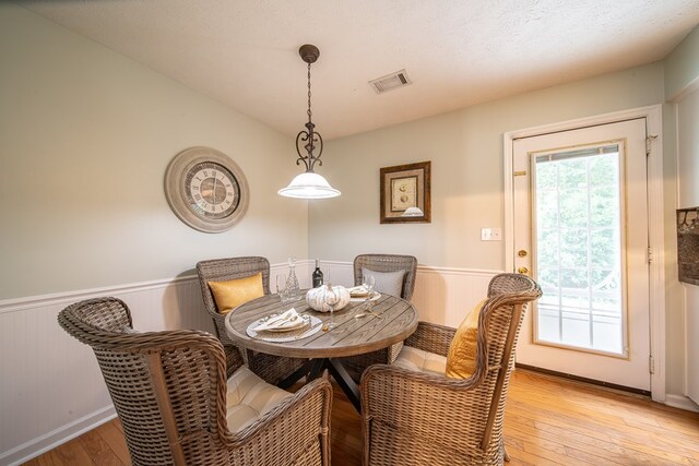 dining room featuring lofted ceiling, a textured ceiling, and light wood-type flooring