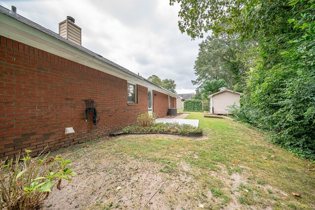 view of yard with cooling unit, a storage shed, and a patio area