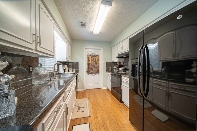 kitchen with sink, backsplash, white cabinets, light hardwood / wood-style floors, and black appliances