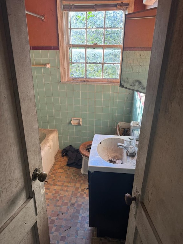 bathroom with tile walls, a bath, vanity, and toilet