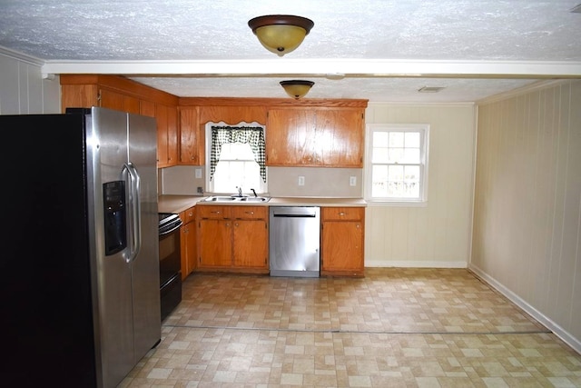 kitchen featuring stainless steel appliances, light countertops, brown cabinetry, a sink, and plenty of natural light