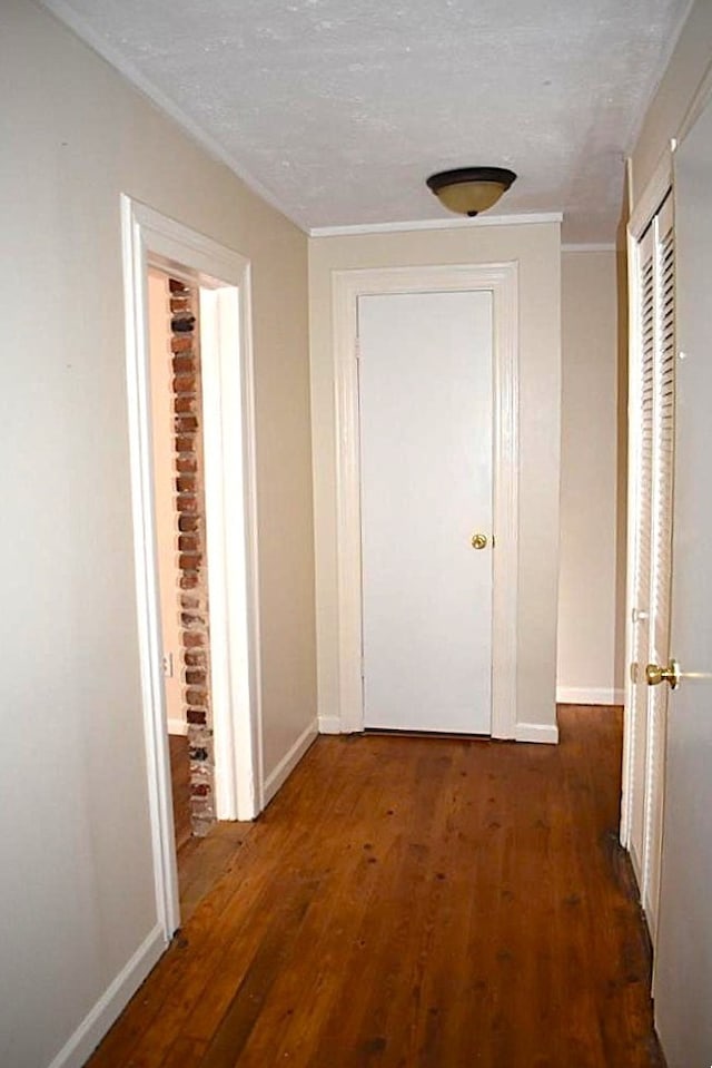 hall with hardwood / wood-style flooring, baseboards, and a textured ceiling