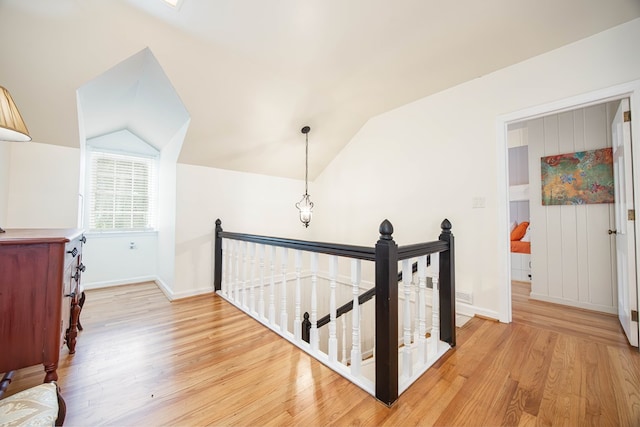 hall with lofted ceiling and light wood-type flooring